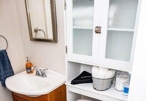 A bathroom with a white sink, a mirror, a towel rack, a cabinet with glass doors, and a basket of towels. - 1BR Mobile Condo with Community Pool  (Mobile)