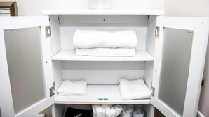 Un meuble blanc à trois étagères, chacune contenant des serviettes blanches pliées.