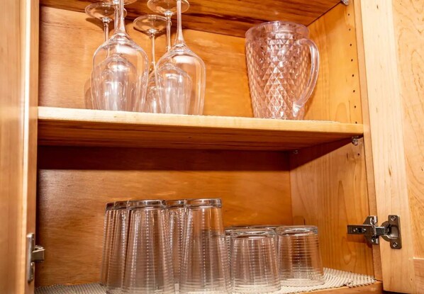 Ein Holzkabinett mit Regalen, auf denen klare Weinkelche und eine Kristallkaraffe stehen.