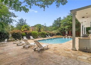A swimming pool with lounge chairs, a stone patio, and a covered area with a grill. - 1BR Mobile Condo with Community Pool  (Mobile)