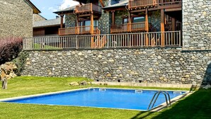 Un bâtiment en pierre doté d’une piscine et d’une terrasse en bois.