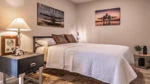 A bedroom with a bed, bedside table, lamp, and two wall-mounted artworks. - ✈️ Full Stop Landing | Aviation Retreat Near Pinehurst (Carthage)