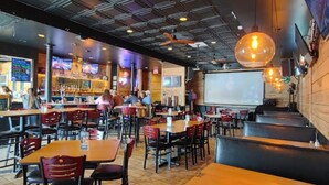 A restaurant with multiple tables and booths, a bar area, and a projection screen on the wall. - ✈️ Full Stop Landing | Aviation Retreat Near Pinehurst (Carthage)
