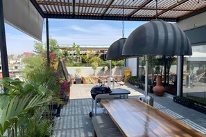 Relax in style with a city view, a grill, and comfortable seating under a spacious umbrella.