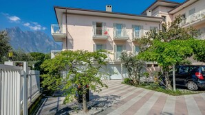 A multi-story residential building with balconies, a paved courtyard, and a mountain backdrop. - Casa al Cor - Star in Torbole, Torbole sul Garda, Italy (Torbole sul Garda)
