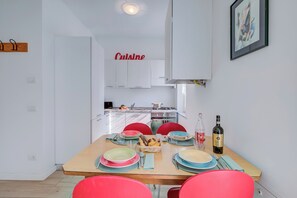 Una cucina moderna con mobili bianchi, un tavolo da pranzo apparecchiato con piatti, bicchieri e una bottiglia di vino.