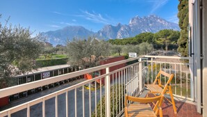 Un balcon avec vue sur les montagnes, une chaise et une pancarte indiquant « OLBERG LECHIO ».
