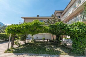 Une cour intérieure agrémentée d’une pergola, de plantes en pot et d’un bâtiment doté de balcons.