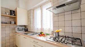 Une cuisine moderne équipée d’une cuisinière à gaz, d’un four à micro-ondes et d’étagères en bois.