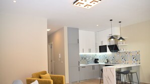 A modern kitchen with white cabinets, a marble island, and pendant lighting. - Pastel Apartment, Lalzit Bay, Albania (Lalzit Bay)