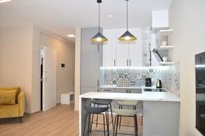Enjoy a compact kitchen with a central island, sink, and kettle, complemented by a vibrant backsplash and pendant lighting.