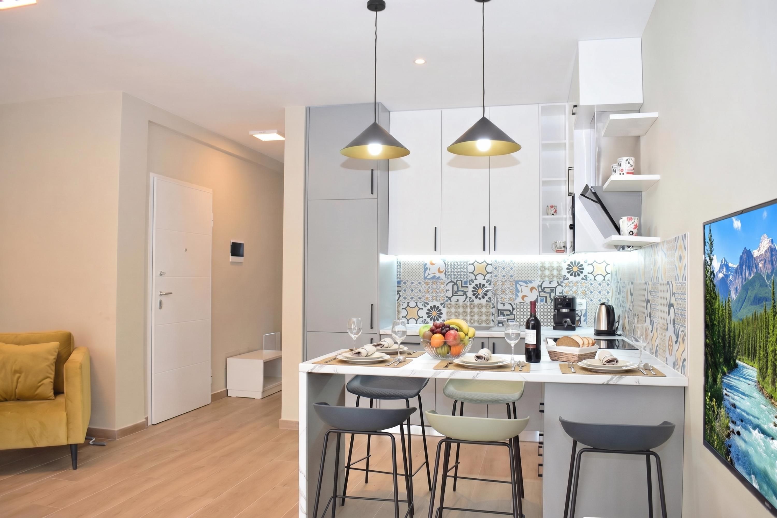 Une cuisine moderne dotée d’un îlot central, de tabourets de bar, de luminaires suspendus et d’une grande fenêtre offrant une vue sur les montagnes.