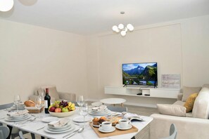 Een moderne eetruimte met een ontbijttafel, een televisie en een bank.