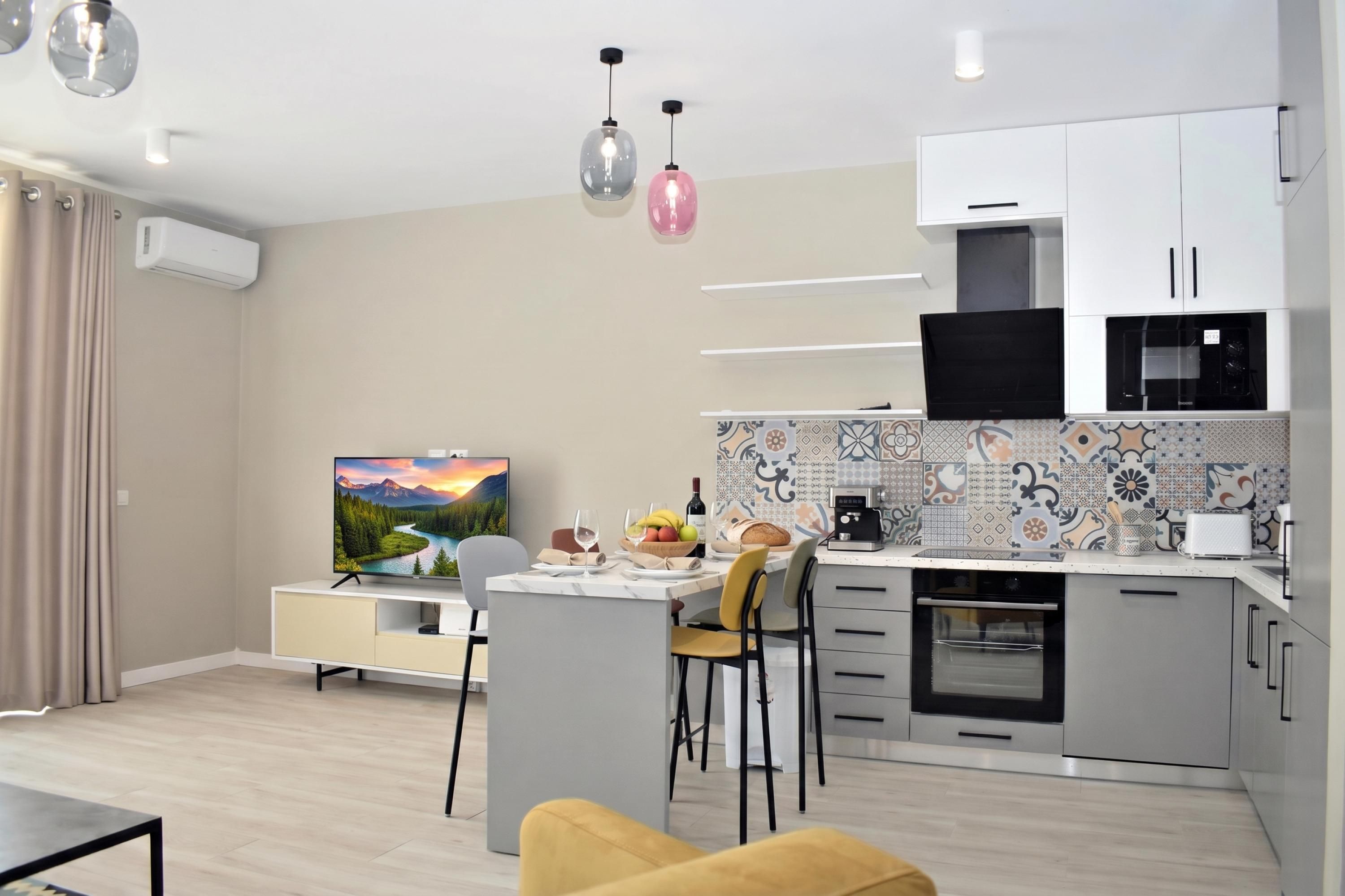 Una cocina moderna con comedor, televisor de pantalla plana y cafetera.
