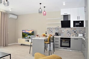 A modern kitchen with a dining area, a flat-screen TV, and a coffee machine. - White Moon Apartment 301, Lalzit Bay, Albania (Lalzit Bay)