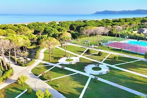 Um parque com quadra de basquete, caminhos para caminhar e vista para o mar.