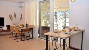 Un comedor moderno con una mesa de madera, sillas y un ventanal de vidrio que da a un balcón exterior.
