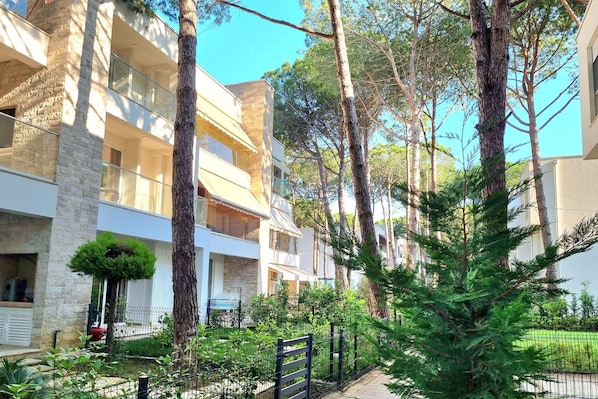 A multi-story residential building with balconies, surrounded by trees and greenery. - Swiss Sweet Apartment 297, Lalzit Bay, Albania (Lalzit Bay)