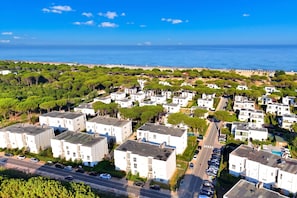 A residential area with modern buildings, a beach, and a clear sky.
