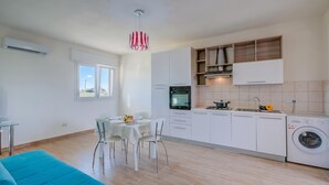 A modern kitchen with white cabinets, a dining table with chairs, a washing machine, and a ceiling light fixture. - Le Bianche Apt1 with Garden Near The Sea, Manduria, Italy (Manduria)