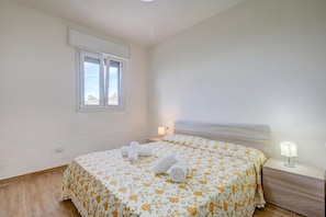 Une chambre à coucher avec un lit, une table de chevet, une lampe et une fenêtre.