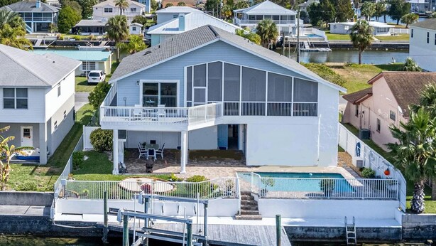 A two-story house with a balcony, a dock, and a swimming pool.