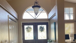 A hallway with a double door, a small cabinet, and a patterned chair.