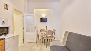 A compact living space with a kitchenette, a dining area with a table and chairs, and a grey sofa. - Villa Belvedere by Interhome (Janské Lázně)