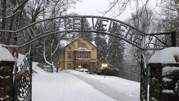 Una entrada cubierta de nieve con una reja de metal y un cartel que dice "BELVEDERE".