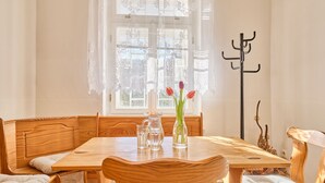 Una mesa de madera para comer con un jarrón de tulipanes, una jarrilla y vasos.