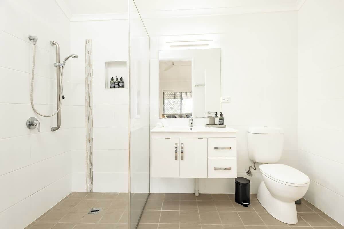 A modern bathroom with a shower, toilet, and vanity.