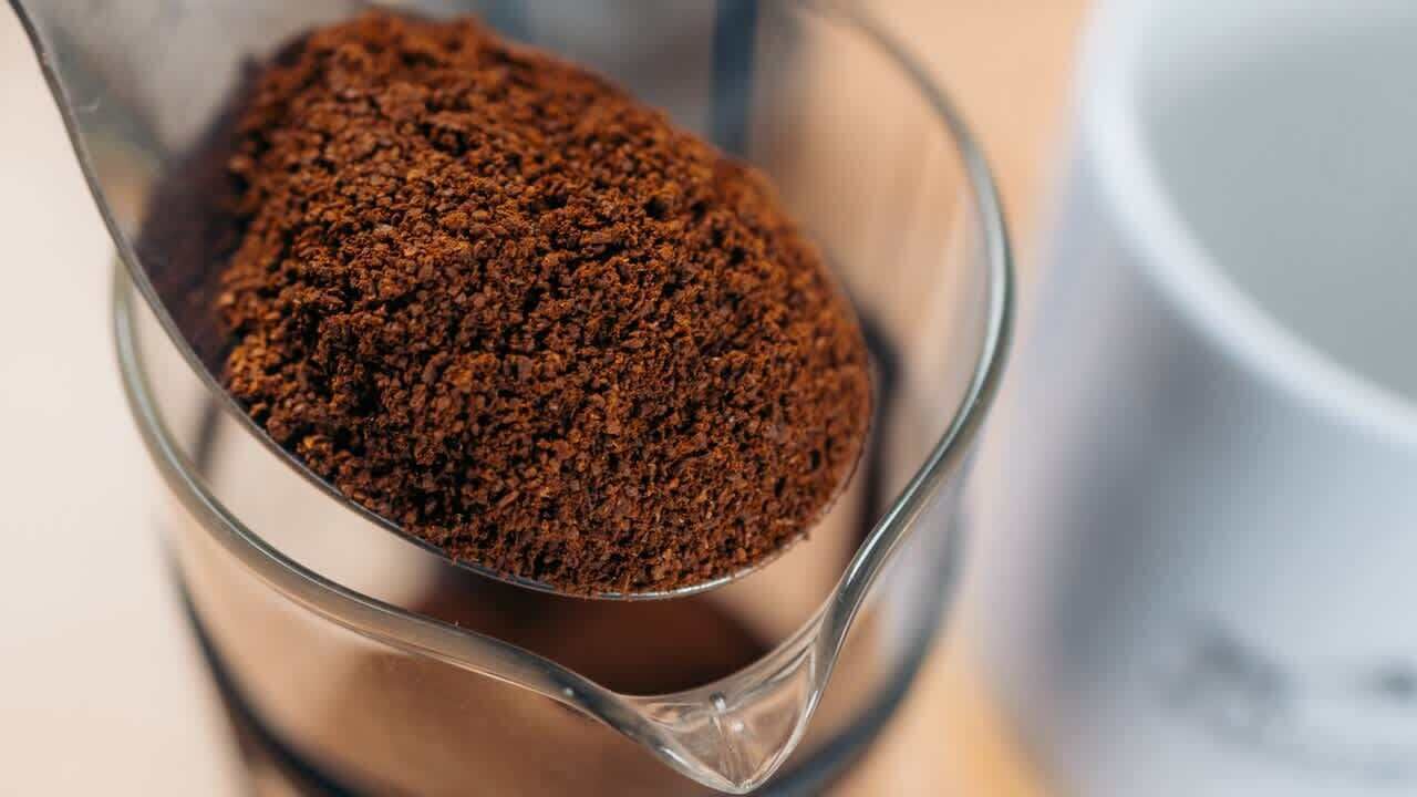 A clear glass measuring cup filled with a brown powdery substance.