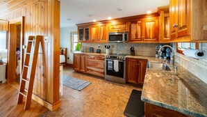A modern kitchen with wooden cabinets, stainless steel appliances, and a granite countertop.