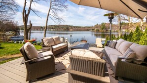 An outdoor patio with wicker furniture, a covered area, and a lake view.