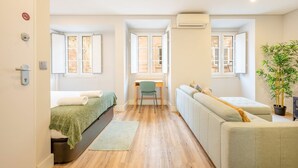 Eine kompakte Studio-Wohnung mit Bett, Schlafsofa, Schreibtisch und Fenster.