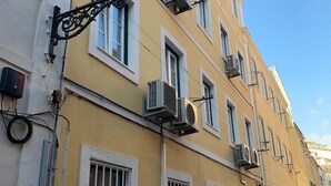 Ein gelbes Gebäude mit vielen Fenstern, Klimaanlagen und einer Straßenlaterne.