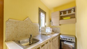Cocina compacta con un lavamanos doble, horno empotrado y ventana que proporciona luz natural.