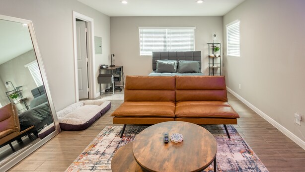 A modern living room with a sofa, two round tables, and a large mirror. - Cozy Downtown, Montrose Studio!
Free parking ! (Houston)
