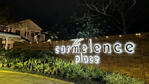 Een bord met de tekst 'Carmelence Place', met een houten gevel en verlichte letters.