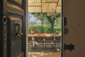 An open door leading to an outdoor dining area with tables and chairs, surrounded by greenery and a view of the landscape. - I Cipressi, 5 bedrooms with pool near Cortona (Cortona)
