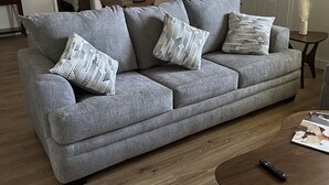 A grey sofa with patterned cushions, a wooden coffee table, and a remote control on it. - Close to hiking trails, Central home, 3 bedrooms! (Phoenix)