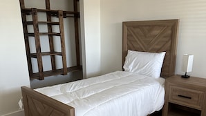 A wooden bed with a headboard, a nightstand with a lamp, and a wooden floor. - Close to hiking trails, Central home, 3 bedrooms! (Phoenix)