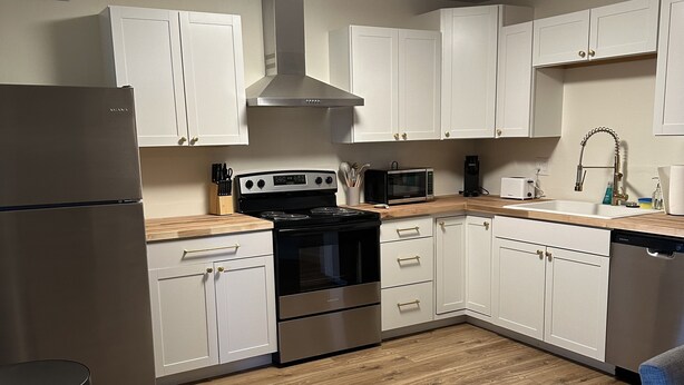 A modern kitchen with white cabinets, stainless steel appliances, and a wooden floor. - Close to hiking trails, Central home, 3 bedrooms! (Phoenix)