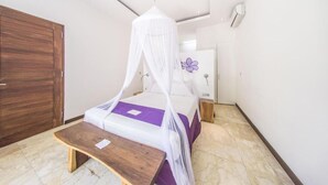 Une chambre à coucher avec un lit sous un dais, un banc en bois, une porte et un climatiseur fixé au mur.