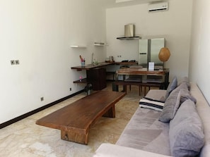 Una sala moderna con un banco de madera, un sofá y una zona de cocina con estufa y fregadero.