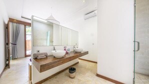 Une salle de bain moderne avec un grand miroir, deux lavabos, un porte-serviettes et une poubelle.