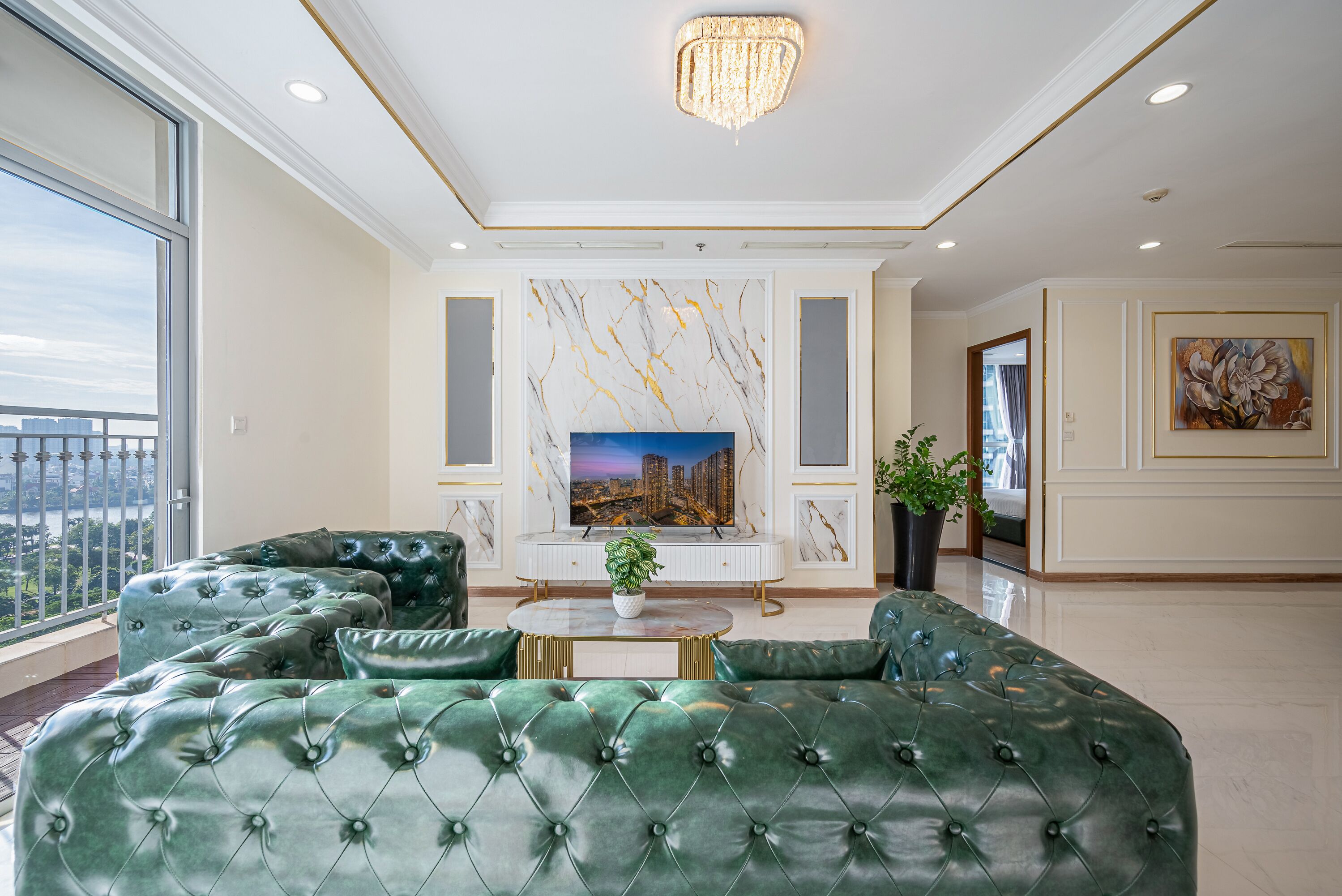 Un salon spacieux avec un grand canapé vert, un téléviseur à écran plat et un mur décoratif en marbre.
