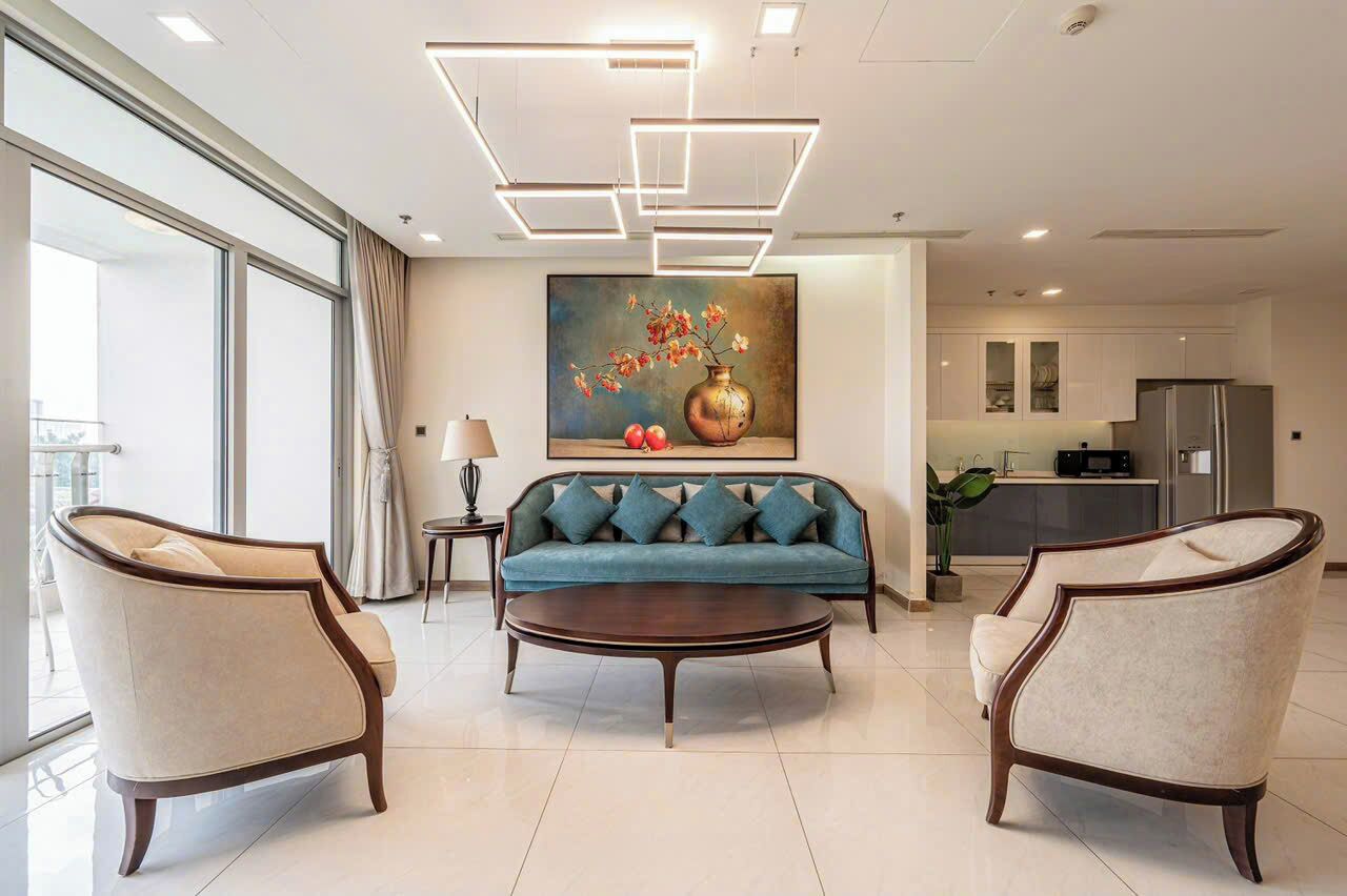 Una sala moderna con un sofá, dos sillones, una mesita de centro y un cuadro de flores en la pared.