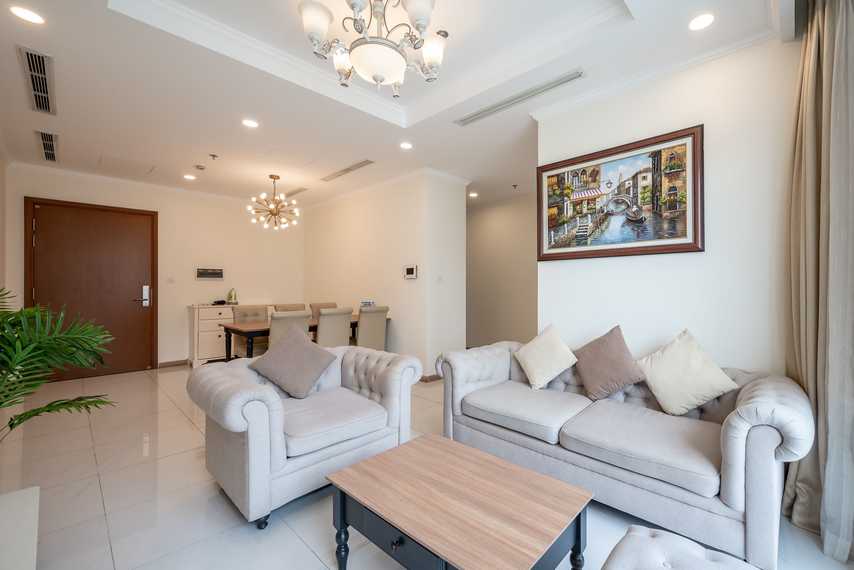A modern living room with two sofas, a wooden coffee table, and a chandelier.