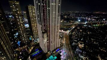 A high-rise building with a modern design, featuring vertical lines and illuminated windows.